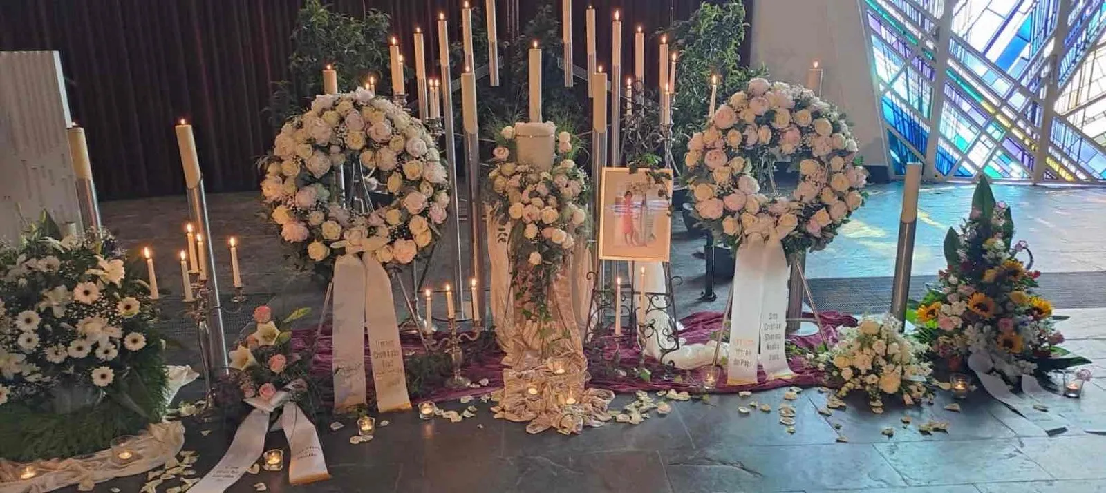 Trauerdekoration mit cremefarbenen Rosenkränzen und Kerzenlicht